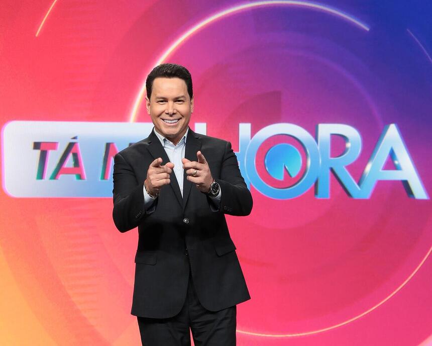 Marcão do Povo em frente ao telão do Tá na Hora, novo programa do SBT. Ele aponta para a frente e sorrir