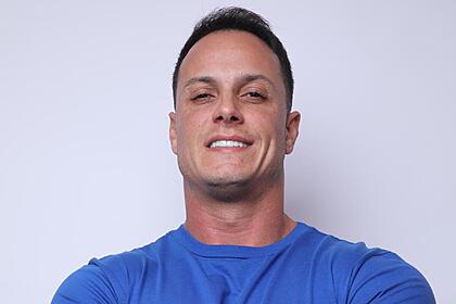 Fellipe Vilas de camisa azul sorrindo em foto promocional do A Grande Conquista 2