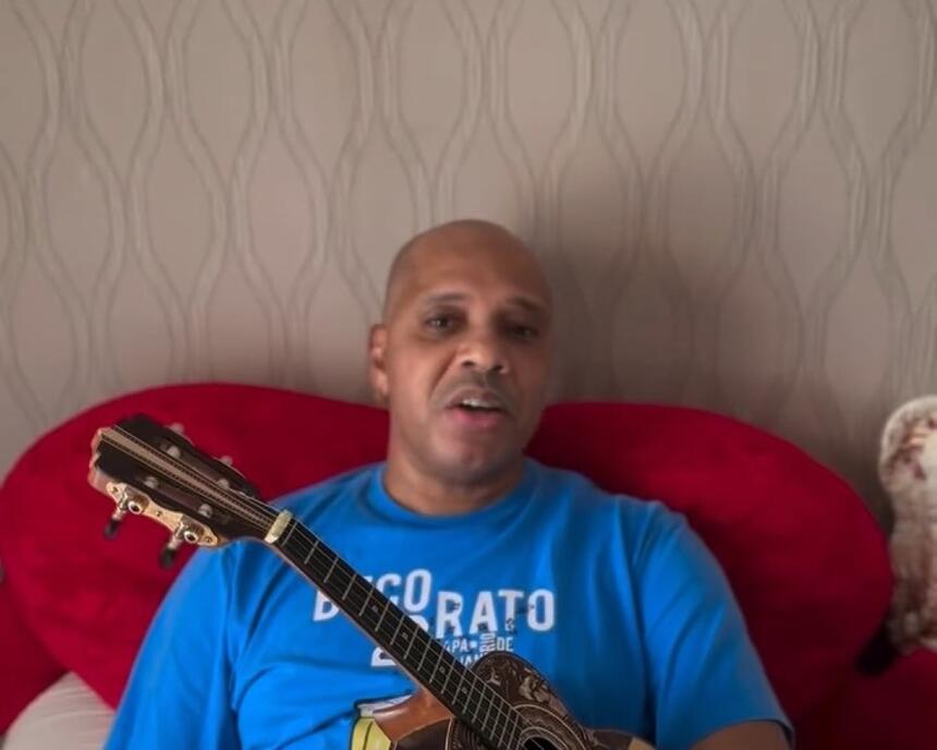 Anderson Leonardo do Molejo tocando cavaquinho deitado em uma cama