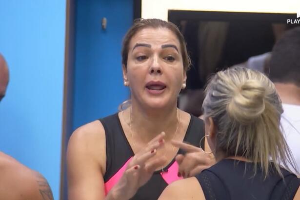 Andreia levanta a mão em discussão com Nadya na cozinha da casa azul do A Grande Conquista 2