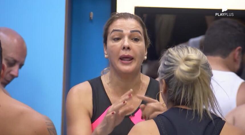 Andreia levanta a mão em discussão com Nadya na cozinha da casa azul do A Grande Conquista 2