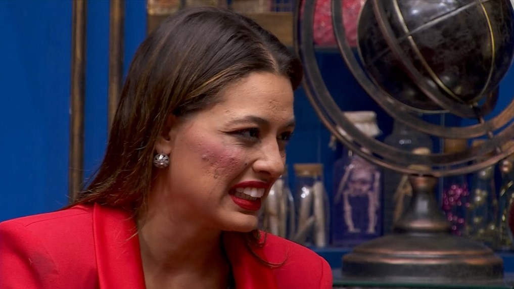 Beatriz, de conjunto e batom vermelho, sorrindo na sala do BBB 24
