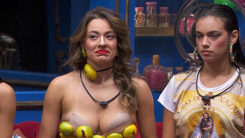 Beatriz com o top de cascas de laranja ao lado de Alane no sofá do BBB 24