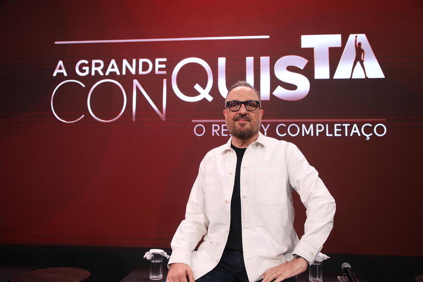 Rodrigo Carelli em frente ao logo do A Grande Conquista na coletiva de imprensa