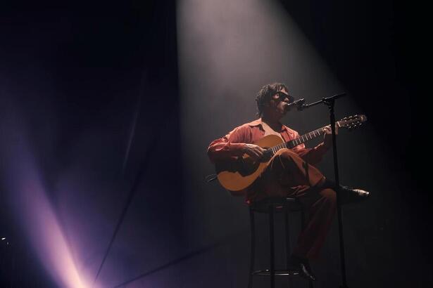 Djvan sentado, tocando violão, ao vivo em Maceió