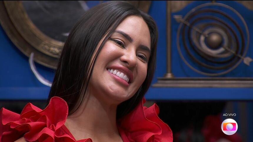 Isabelle, de vestido vermelho, sorrindo na sala do BBB 24 na final do programa