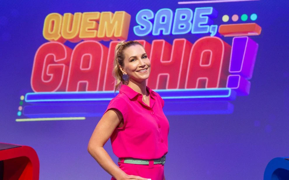 Anne Lottermann aparce em frente do telão do programa Quem Sabe, Ganha!
