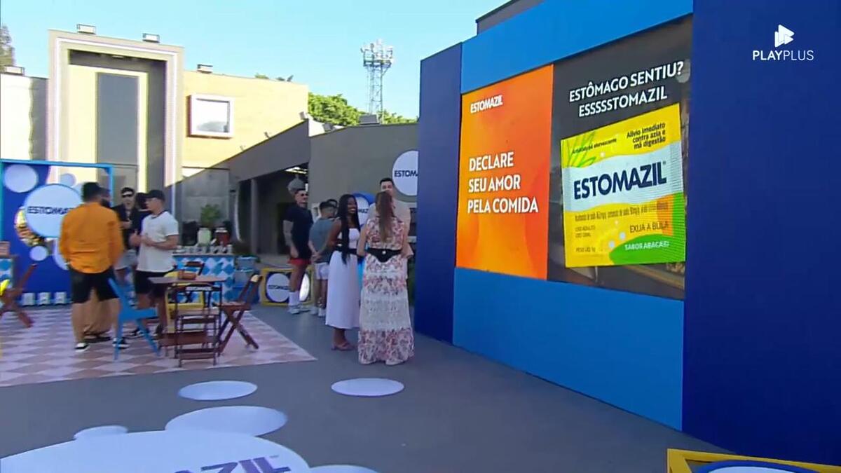 Cenário da atividade patrocinada pelo Estomazil na área externa da Mansão do A Grande Conquista contendo mesinhas, pastel, hambúrguer e muito mais