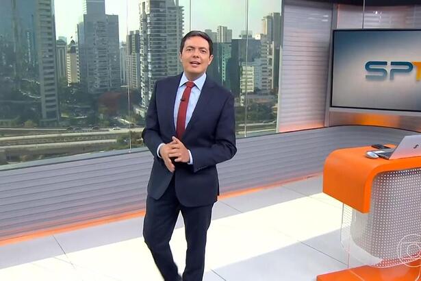 Alan Severiano sorrir enquanto anda pelo cenário do SP1 na TV Globo São Paulo