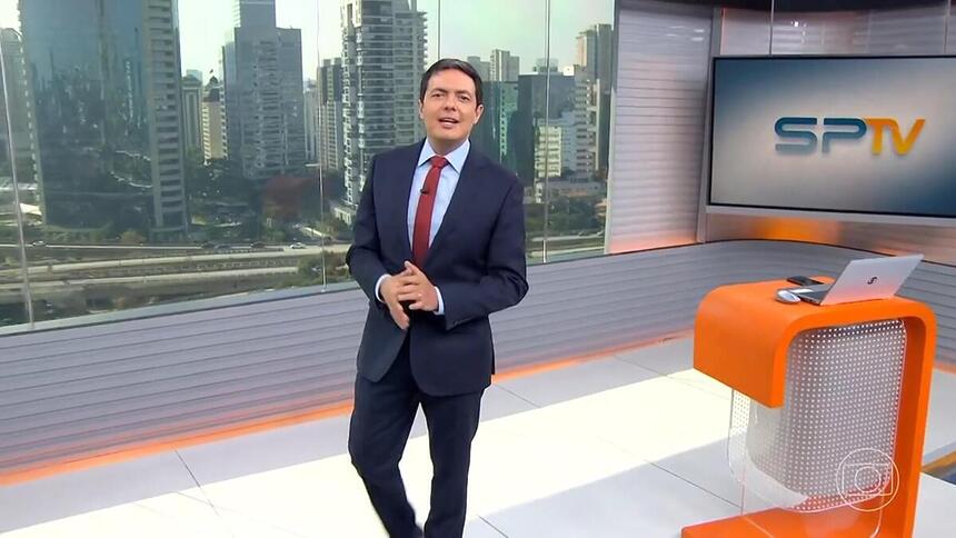 Alan Severiano sorrir enquanto anda pelo cenário do SP1 na TV Globo São Paulo