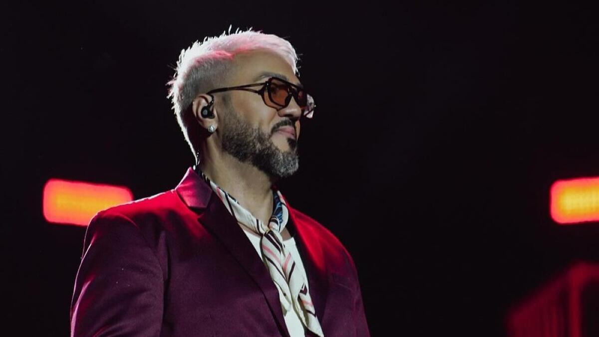 Belo de óculos escuro e terno vermelho em show