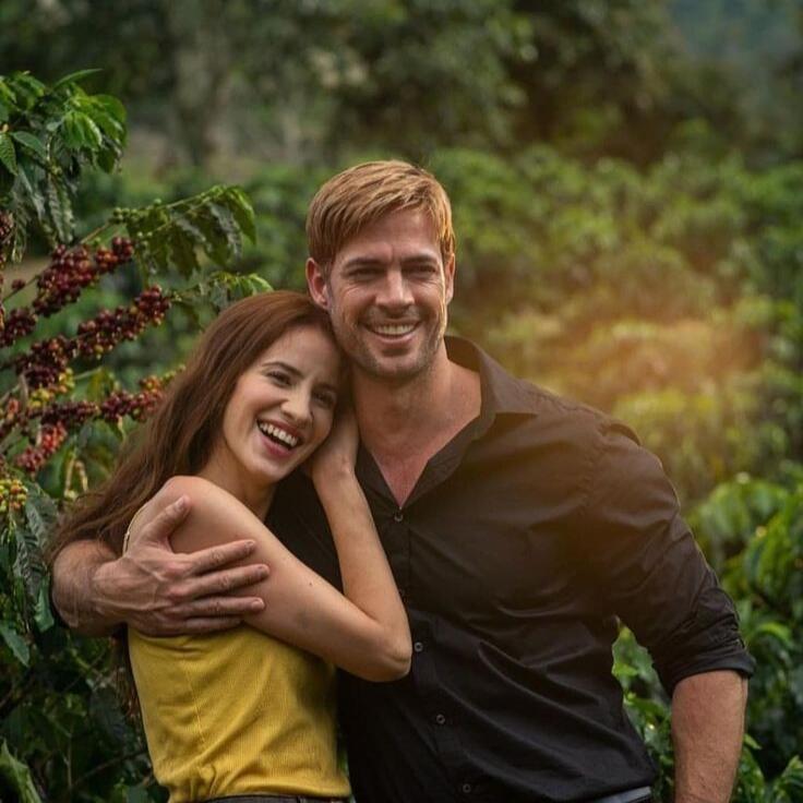 William Levy e Laura Londoño abraçados e sorrindo em um cafezal, nos bastidores da novela Café com Aroma de Mulher