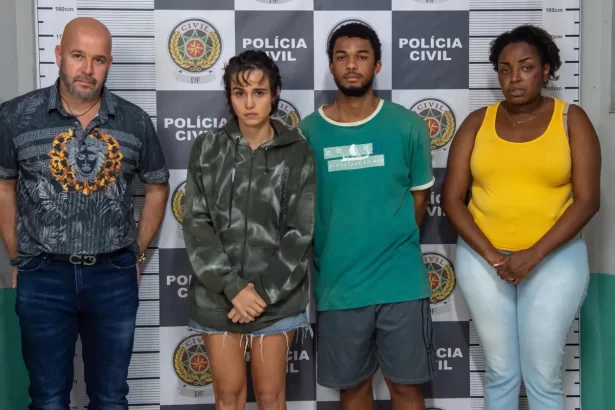 Imagem mostra o elenco principal com as mãos algemadas em frente ao painel da Polícia Civil.