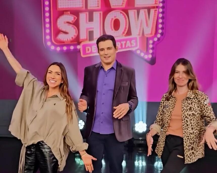 Patrícia Abravanel com os braços abertos, Celso Portiolli ao centro e Rebeca Abravanel no cenário da Live Jequiti Show de Ofertas