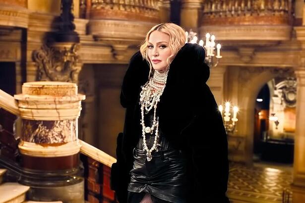 Madonna subindo escadas, de casaco preto, em comercial do banco Itaú. Cantora não ajudou o Rio grande do Sul