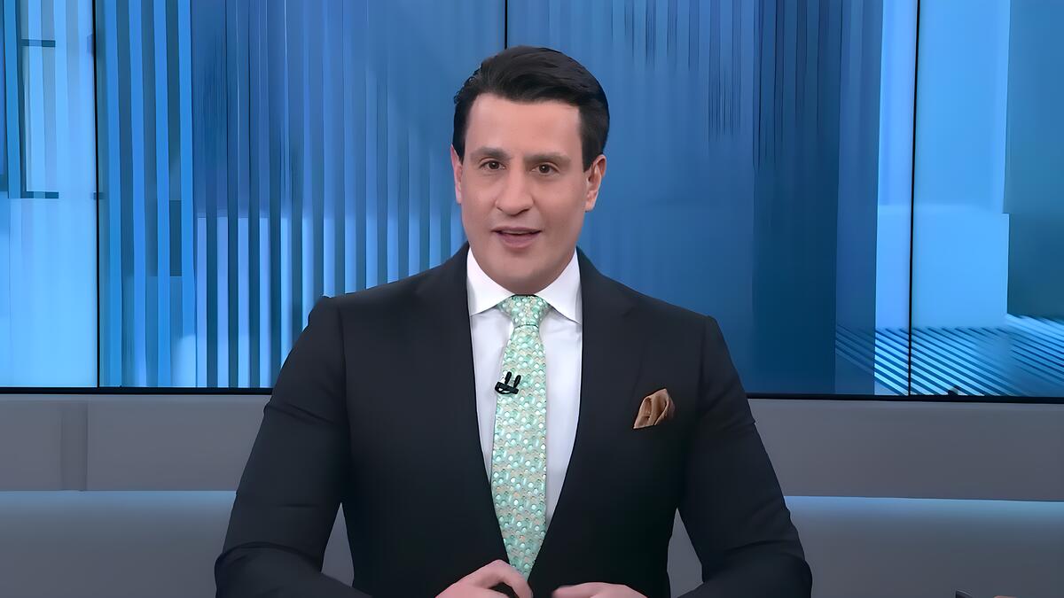 Tiago Pavinatto sorrindo no cenário da Jovem Pan