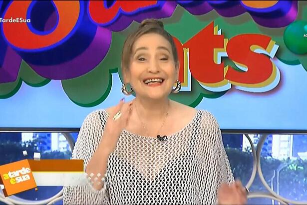 Sonia Abrão sorrindo em frente ao logo do A Tarde é Sua 18 anos