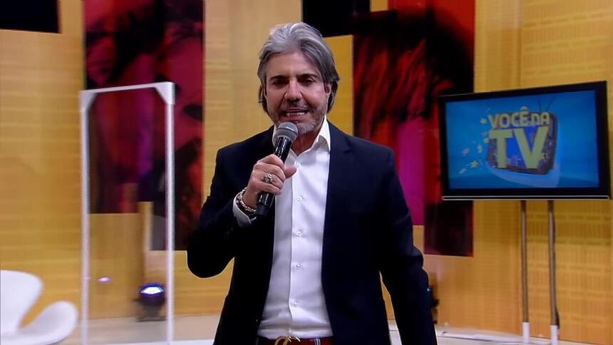 João Kleber segura microfone no centro do palco do Você na TV