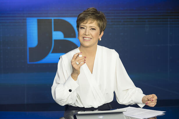 Christina Lemos sorrindo na bancada do Jornal da Record