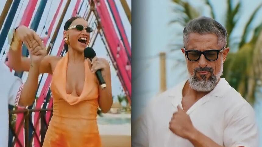 Débora Nascimento entra no palco do Caldeirão em Curaçao sorrindo enquanto Marcos Mion está de óculos escuro também sorrindo