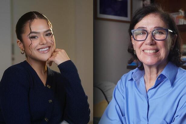 Maisa Silva de blusa preta, apoiando o queixo na mão dividindo tela com Lilia Cabral que está de blusa azul. As atrizes estão sorrindo.