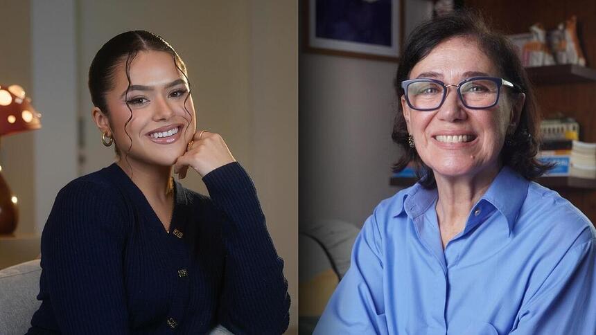 Maisa Silva de blusa preta, apoiando o queixo na mão dividindo tela com Lilia Cabral que está de blusa azul. As atrizes estão sorrindo.