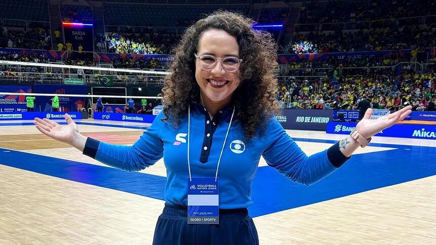 Natália Lara em foto posada em um ginásio de vôlei com o uniforme esportivo da Globo