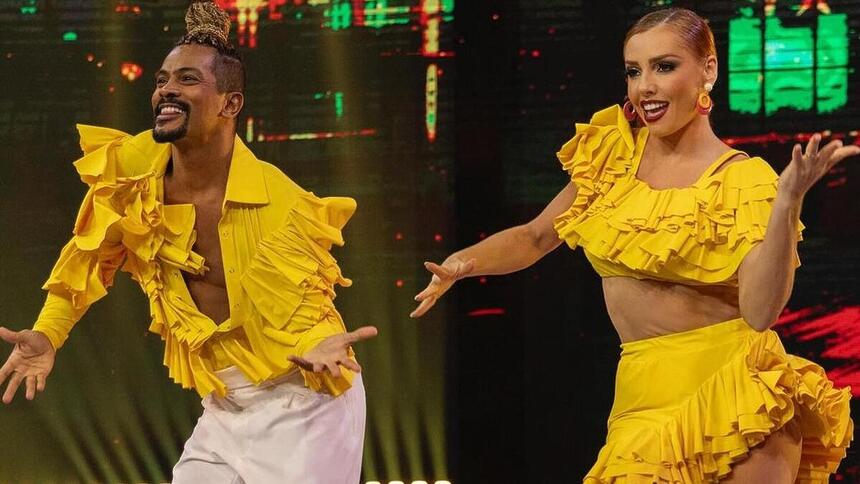 Samuel de Assis e Larissa Parison, com roupa amarela, dançando salsa na Dança dos Famosos