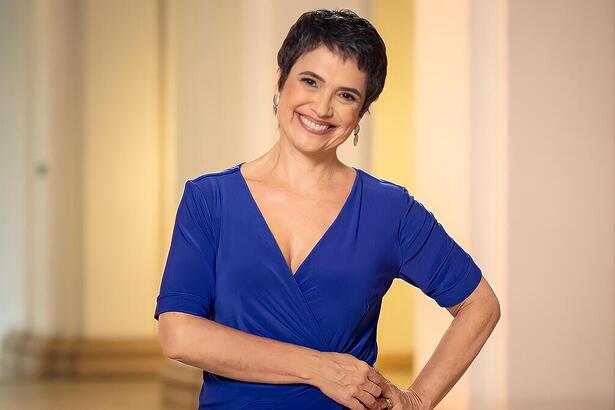 Sandra Annenberg de vestido azul, sorrindo, em gravação da Globo