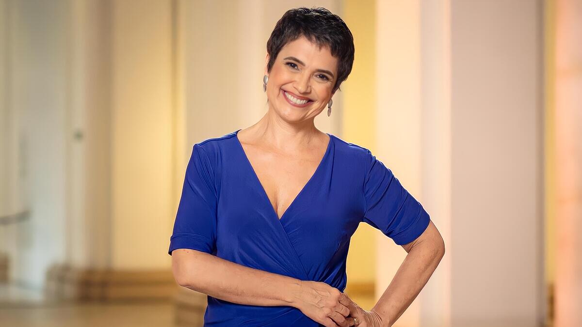 Sandra Annenberg de vestido azul, sorrindo, em gravação da Globo