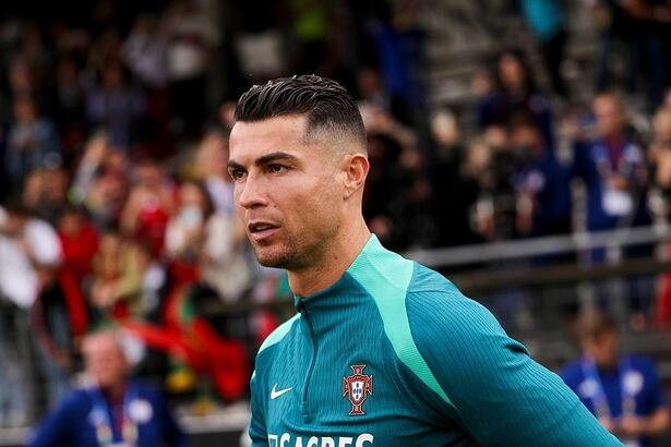 Com roupa do time de Portugal, Cristiano Ronaldo olha sério para o campo de futebol