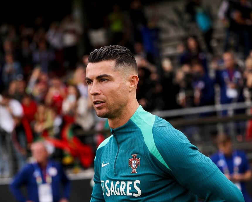 Com roupa do time de Portugal, Cristiano Ronaldo olha sério para o campo de futebol