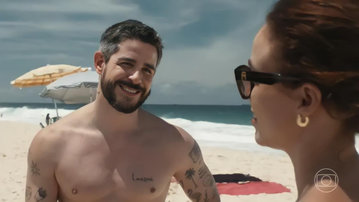 Eriberto sorrindo para Kika na beira de uma praia