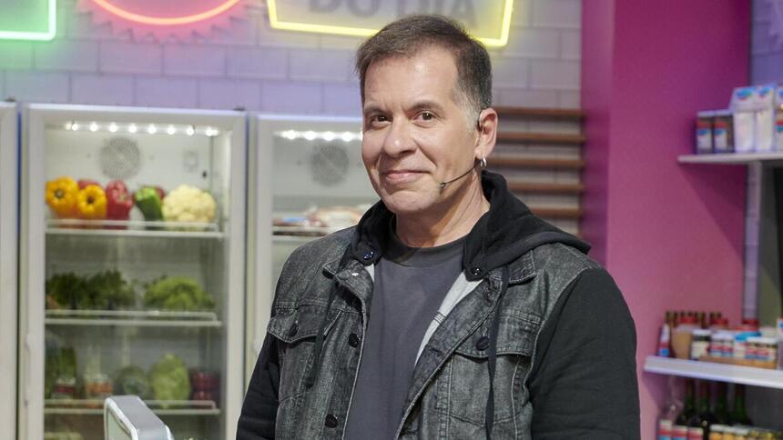 Leandro Hassum sorrindo, nos bastidores de um cozinha, em Minha Mãe Cozinha Melhor programa de TV