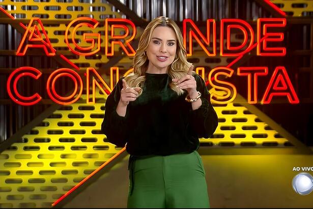 Rachel Sheherazade aponta o dedo para cima e sorrir no cenário do A Grande Conquista 2