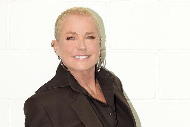 Xuxa de terno preto, sorrindo