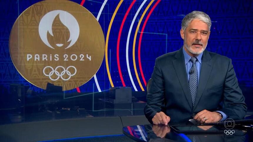 Bonner durante o bloco olímpico do Jornal Nacional, com o logo de Paris 2024 ao fundo da redação