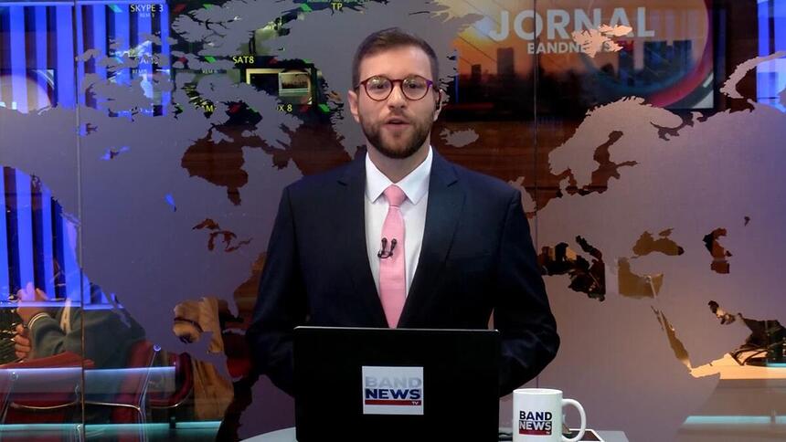 Cassius Zeilmann sorrindo na estreia do novo cenário da BandNewsTV ele está posicionado em frente a redação