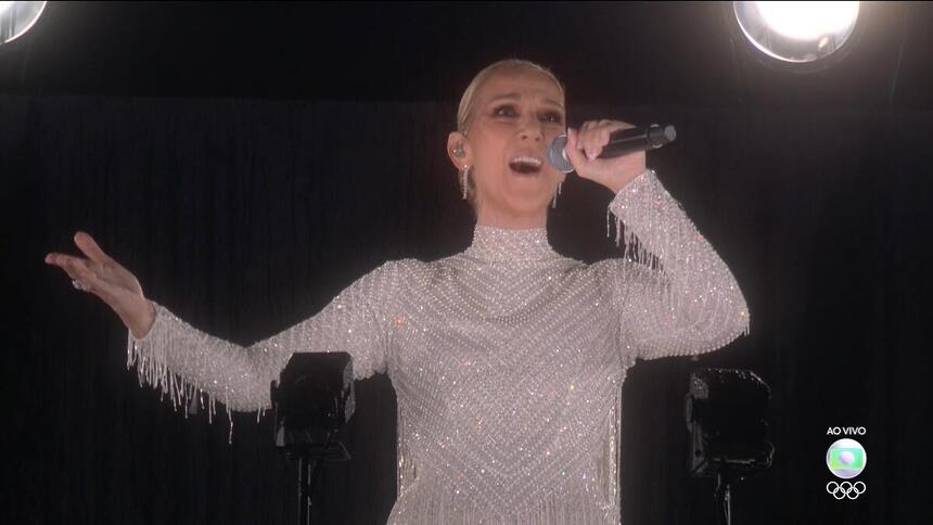 Céline Dion com os braços abertos cantando na Torre Eiffel na abertura da Olimpíada de Paris 2024