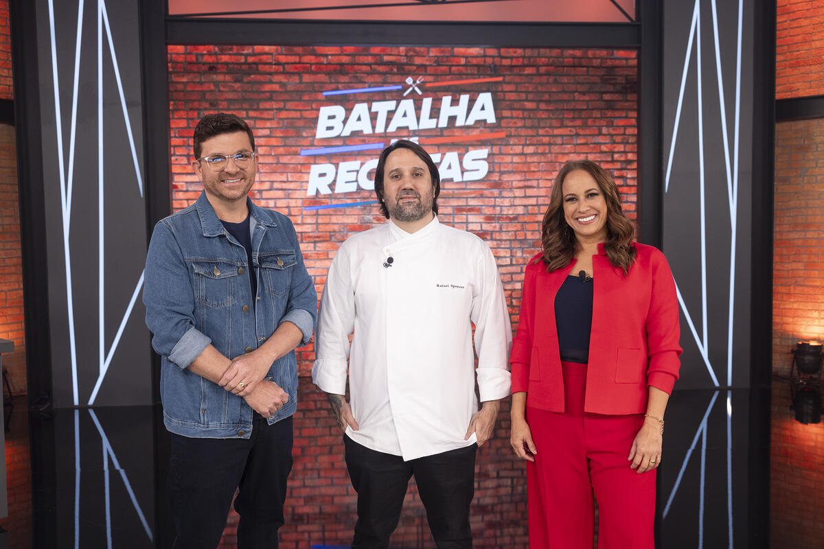 Guga Rocha, Rafael Spencer e Renata Alves sorrindo no cenário do Batalha das Receitas