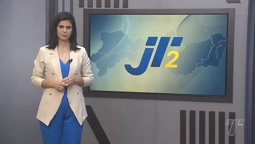 Eliane Nóbrega em frente a tela com o logo do Jornal da Tribuna 2ª edição na afiliada da Band