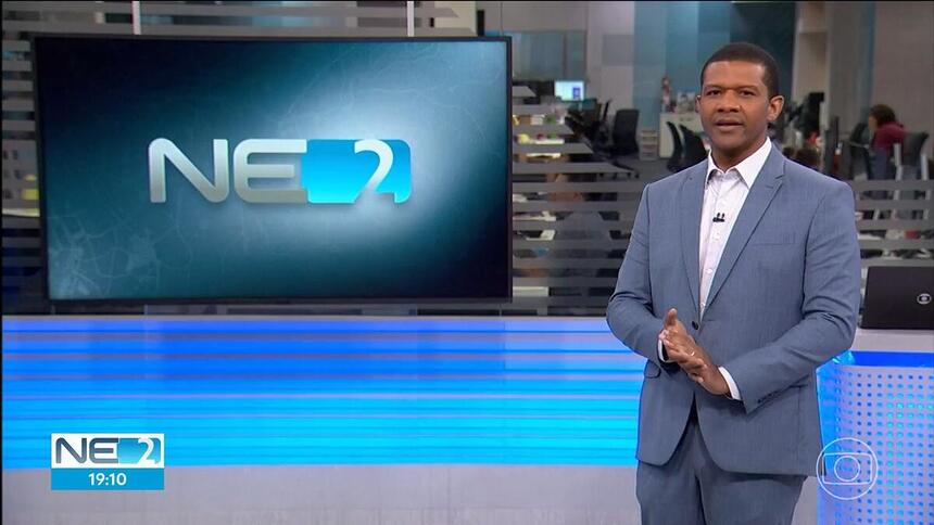 Márcio Bonfim sorrindo em frente ao telão do NE2 na TV Globo Recife