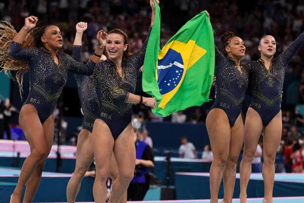 Brasileiras da ginástica com a bandeira do Brasil, celebrando a conquista da medalha