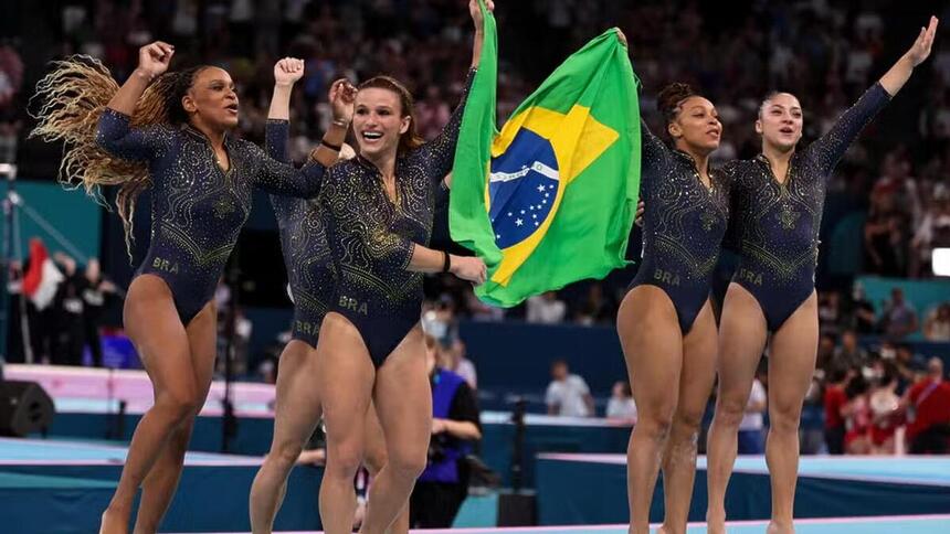 Brasileiras da ginástica com a bandeira do Brasil, celebrando a conquista da medalha