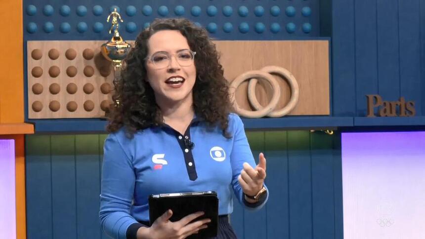 Natália Lara em trecho de transmissão da TV Globo na Olimpíada. Ela segura um tablet na mão direita.