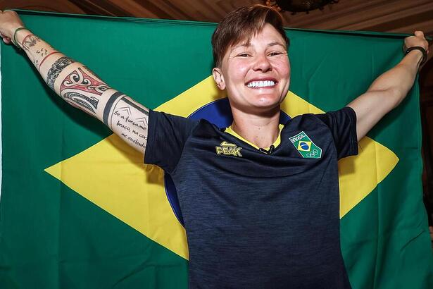 Raquel Kochhann segurando a bandeira do Time Brasil aberta