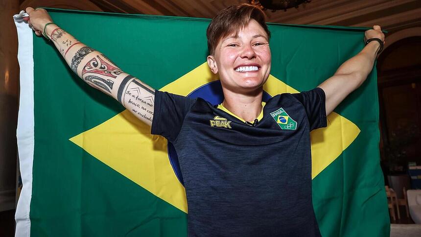 Raquel Kochhann segurando a bandeira do Time Brasil aberta