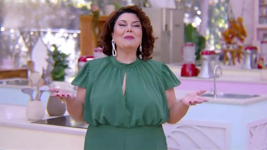 Fabiana Karla de vestido verde no cenário do Bake Off Brasil