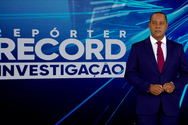 Luiz Fara Monteiro em frente ao logo do Repórter Record Investigação