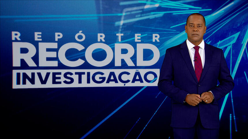 Luiz Fara Monteiro em frente ao logo do Repórter Record Investigação